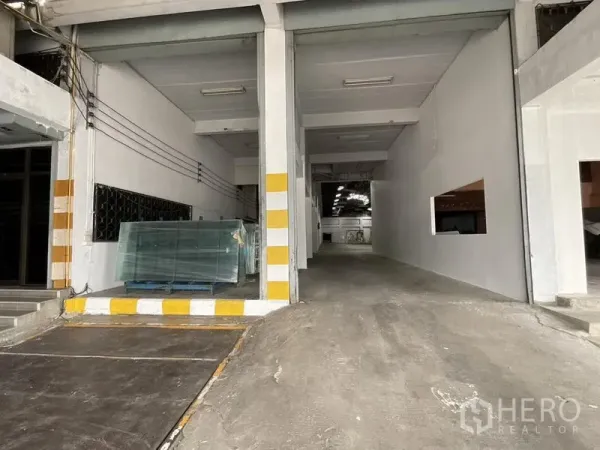 Warehouse for rent in Bang Phli, Samut Prakan - Loading bay with ramp access into the warehouse and safety-striped columns.