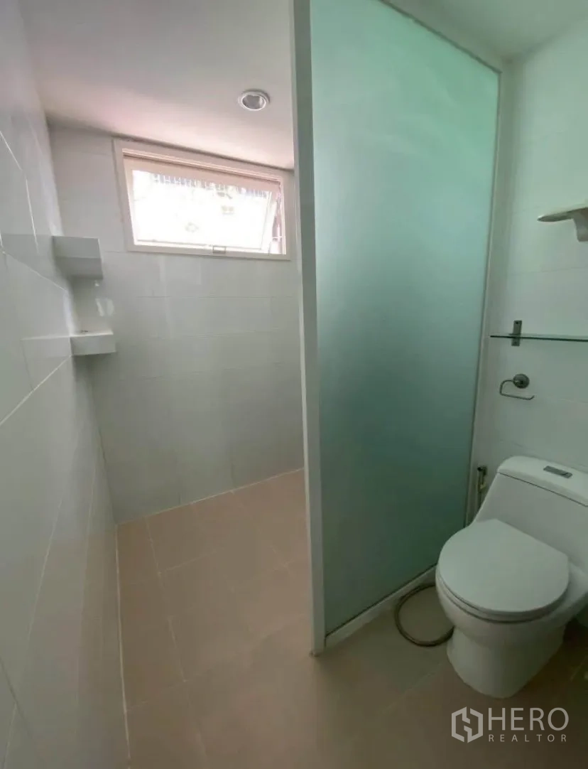 联排别墅 for rent in Phra Khanong, Bangkok - 浴室带磨砂玻璃隔断、坐便器与高窗通风。