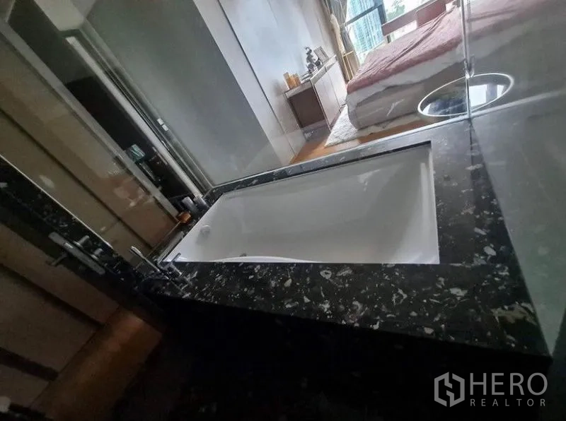 公寓 出租在Khlong Toei, Bangkok - 豪华浴室，深浸式浴缸与深色石材台面。