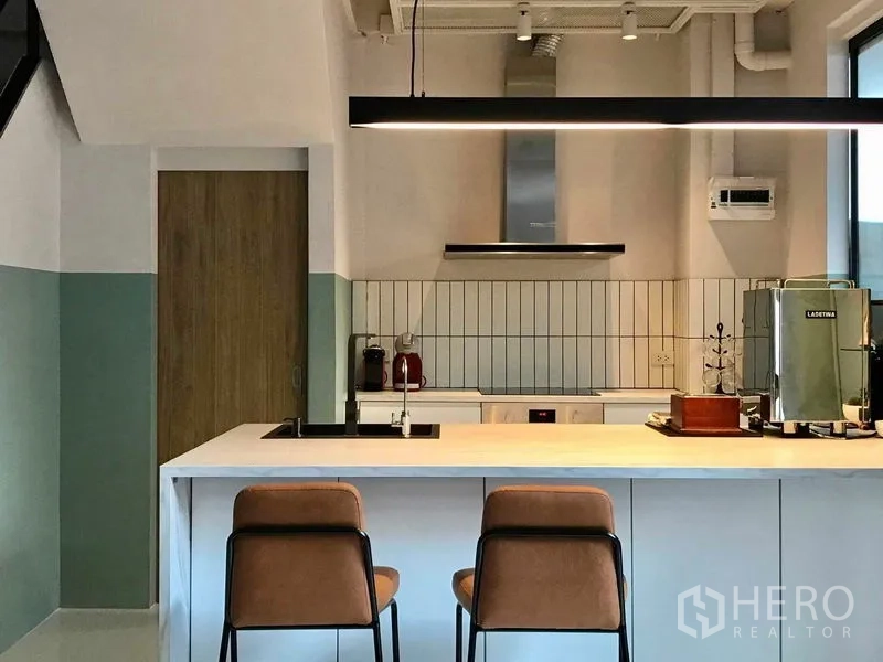 Townhouse for rent or sale in Khlong Toei, Bangkok - Modern kitchen with large island breakfast bar, pendant light and built‑in appliances.