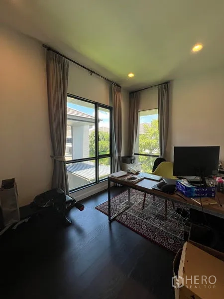 Detached House for rent in Bang Kapi, Bangkok - Bright corner study with large windows, desk and curtains overlooking greenery.