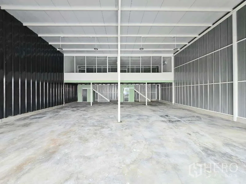 Warehouse for rent in Wang Thonglang, Bangkok - Large empty warehouse bay with full-height metal walls and twin staircases to mezzanine offices.