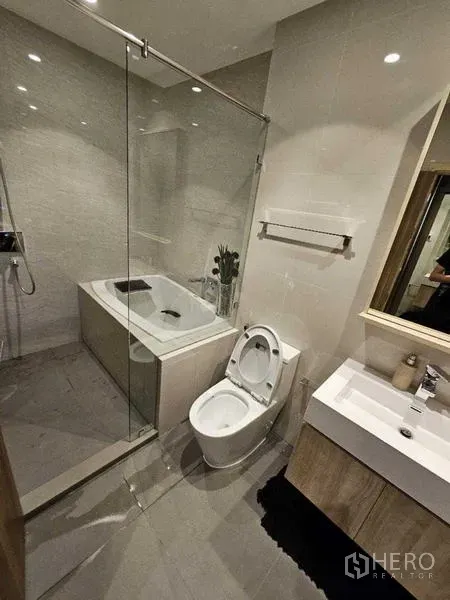 คอนโด ให้เช่า - ห้องน้ำสว่าง มีอ่างอาบน้ำ กั้นกระจก อ่างล้างหน้า และผนังกระเบื้อง