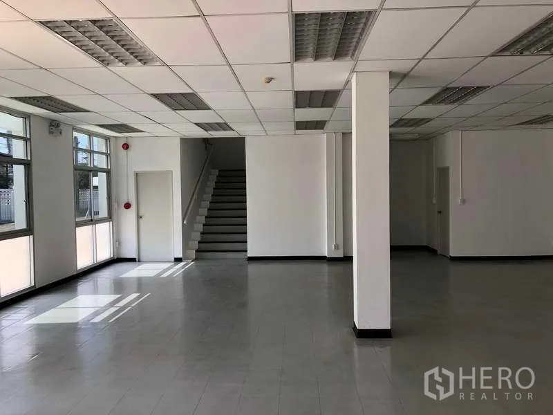 工厂 出租或出售在Phra Nakhon Si Ayutthaya - 明亮的一层办公区，瓷砖地面、窗户与楼梯。