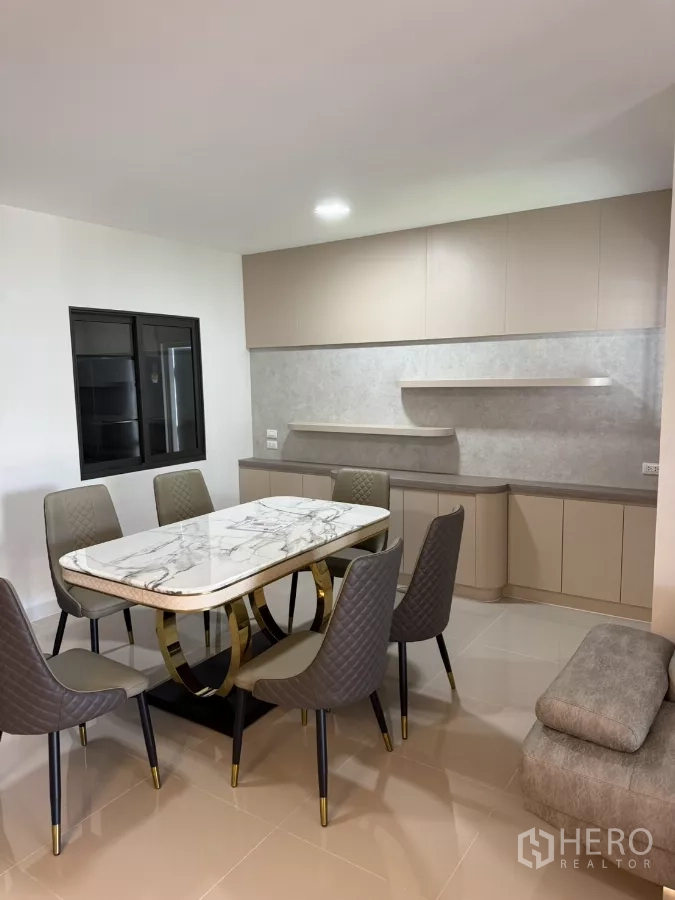 Townhouse for rent or sale in Bang Phli, Samut Prakan - Dining area with marble-top table, six chairs and built-in cabinetry.