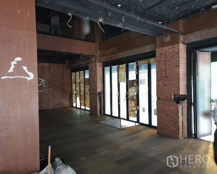 店屋 出租 - 宽敞零售大厅，砖柱、落地窗与木质地面。