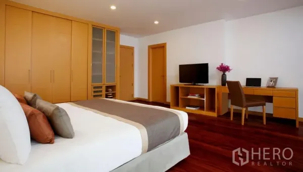 Condominium for rent in Watthana, Bangkok - Large master bedroom with built-in wardrobes, work desk, TV and polished wood flooring.