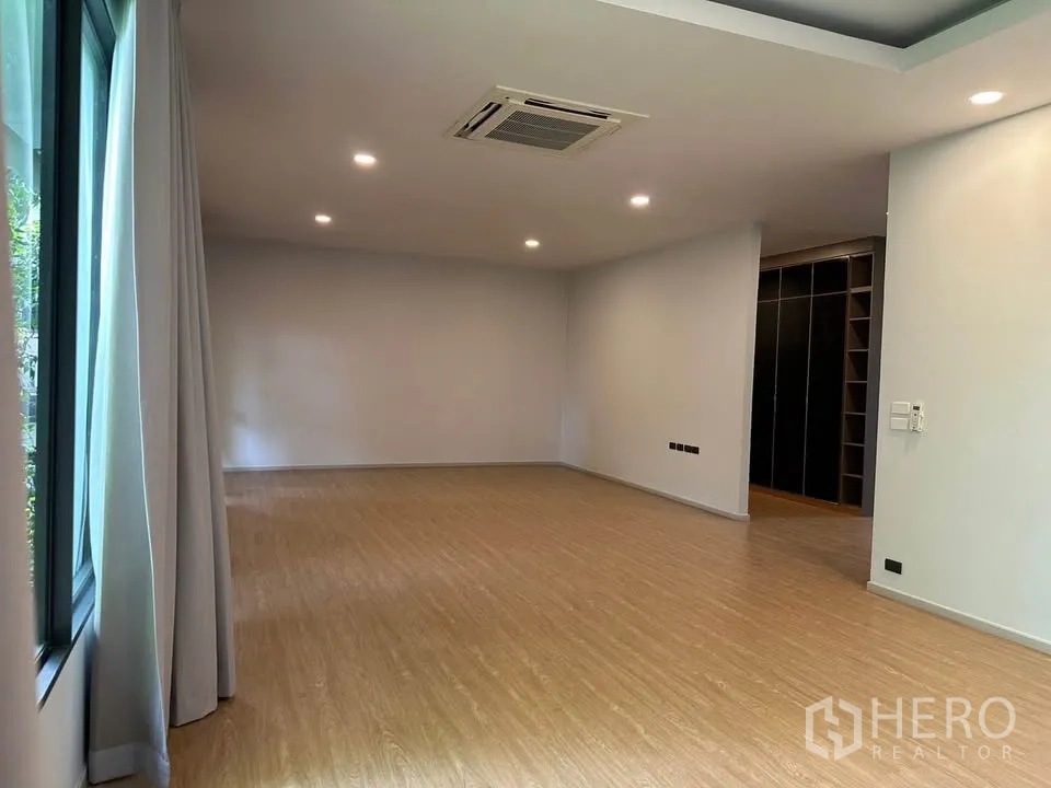 Detached House for sale in Watthana, Bangkok - Large bedroom with wood flooring, ceiling cassette air-conditioning, and a window.