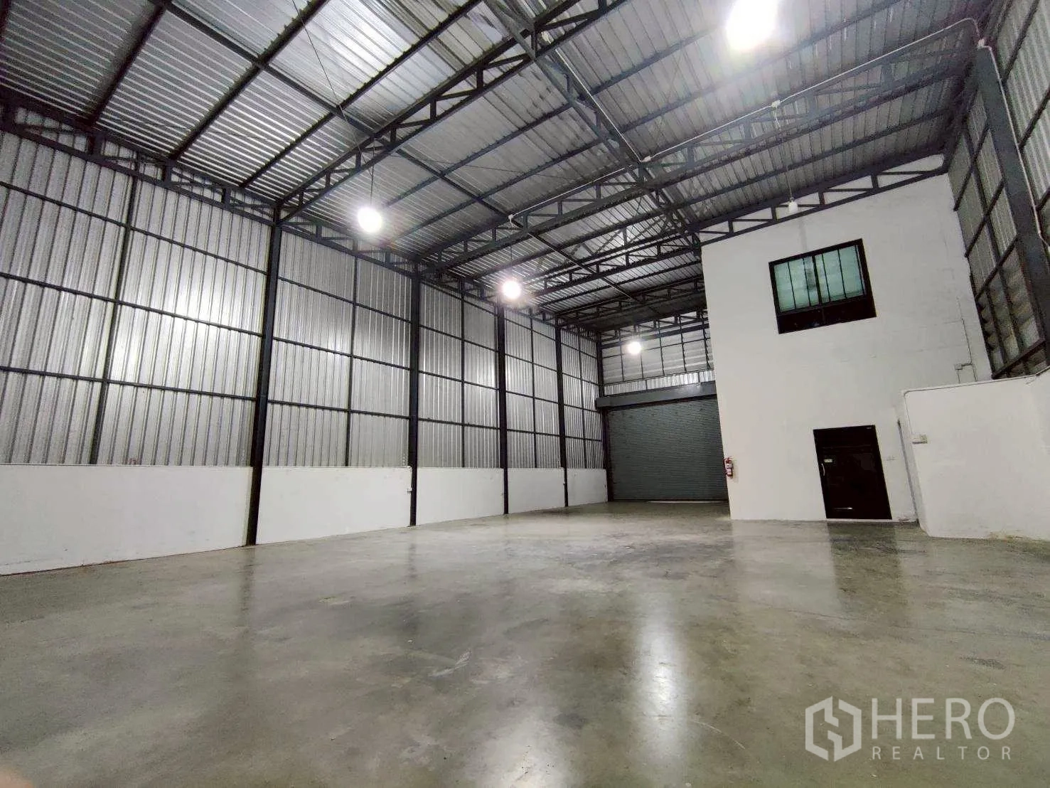 Warehouse for rent in Lam Luk Ka, Pathum Thani - High-clearance steel-framed warehouse hall with concrete slab and office pod.