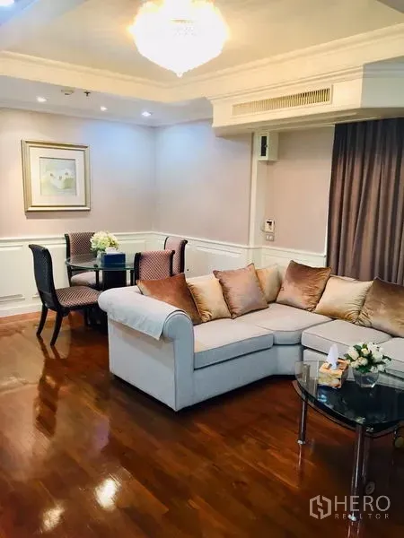 公寓 出售在Watthana, Bangkok - 客厅配L型沙发、水晶吊灯与木地板，角落设小餐桌。