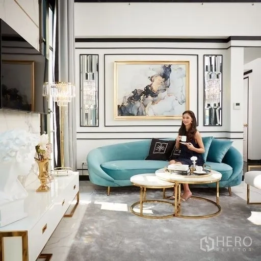 Townhouse for sale - Elegant living room with teal sofa, gold nesting coffee tables, wall art and floor-to-ceiling curtains.