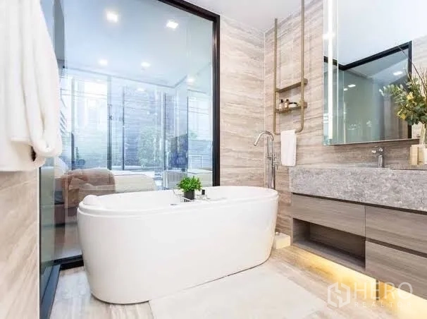 Condominium for rent or sale in Watthana, Bangkok - Luxury bathroom with freestanding bathtub, marble finishes, glass partition and wide vanity.