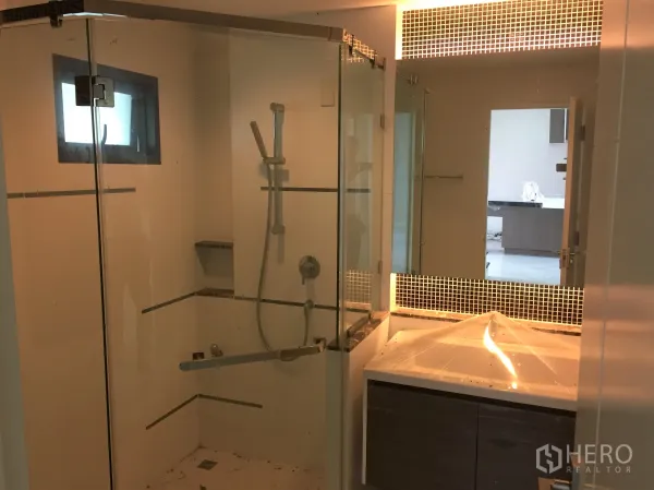 Detached House for rent or sale in Prawet, Bangkok - Contemporary bathroom with glass-enclosed shower and backlit vanity mirror.