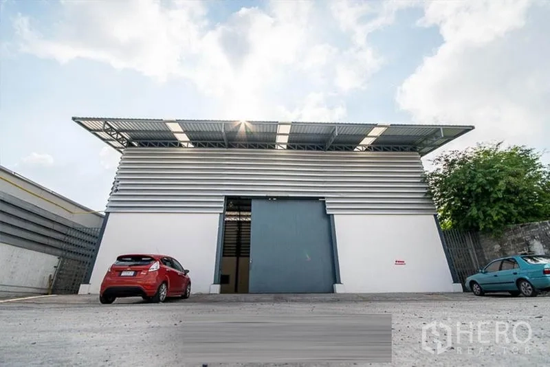 คลังสินค้า ให้เช่า - ด้านหน้าอาคารคลังสินค้า ประตูบานเลื่อนสีน้ำเงินและที่จอดรถ