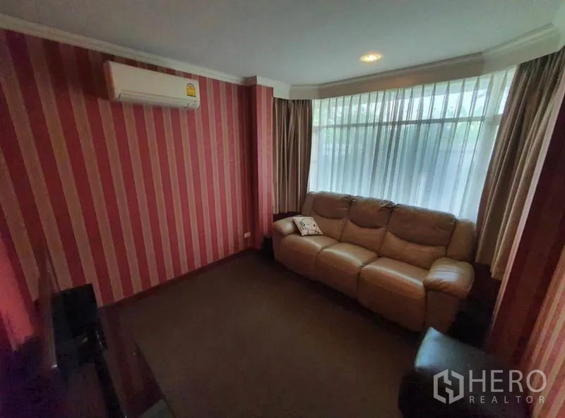 独立式住宅 出售在Sai Mai, Bangkok - 小型电视休闲室，条纹特色墙、大窗与皮沙发。