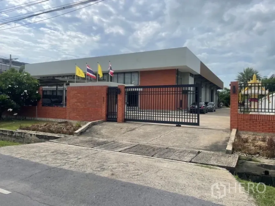 โรงงาน ให้เช่าในMueang Samut Prakan, Samut Prakan - มุมถนนเห็นโรงงานรั้วเหล็กผนังอิฐและพื้นที่จอดรถ