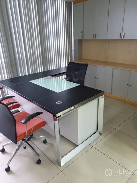 Office Space for rent - Executive desk setup with mesh chair, vertical blinds and built-in cabinetry.