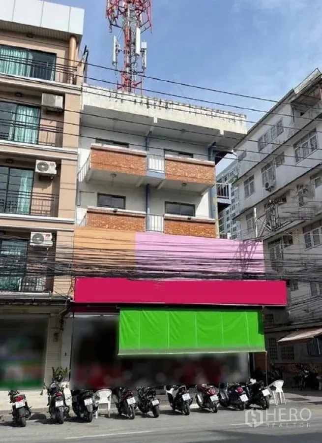 อาคารพาณิชย์ ให้เช่าหรือขายในChon Buri - อาคารพาณิชย์หลายชั้นพร้อมระเบียง กันสาดสีสด หน้ากว้าง มีที่จอดมอเตอร์ไซค์หน้าอาคาร และสายไฟเหนือถนน ในบางละมุง