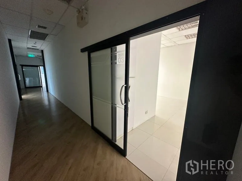Office Space for rent in Ratchathewi, Bangkok - Office corridor with black-framed sliding glass door and emergency exit lights.