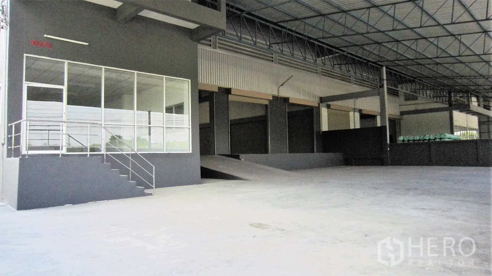 Warehouse for rent in Bang Sao Thong, Samut Prakan - Covered loading bay with ramp and glass-fronted office entrance at the warehouse.