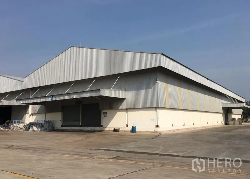 Warehouse for rent in Mueang Samut Songkhram, Samut Songkhram - Expansive warehouse exterior with covered loading bays and a broad truck turnaround area.