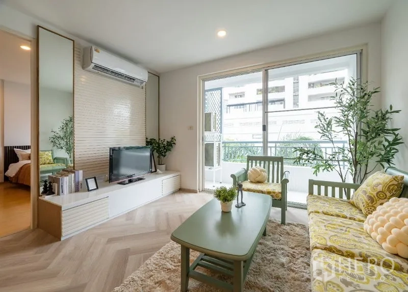 Condominium for sale in Watthana, Bangkok - Living room with TV console, sofa set and sliding glass doors opening to a balcony.