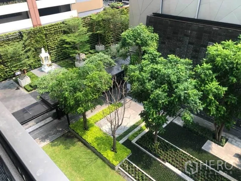 Condominium for sale in Watthana, Bangkok - Lush landscaped condominium courtyard with trees, green walls and paved walkways seen from above.