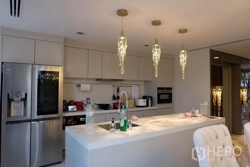 ทาวน์เฮาส์ ให้เช่าในKhlong Toei, Bangkok - ครัวสไตล์ร่วมสมัยโทนขาว ไอส์แลนด์กลางห้อง โคมไฟห้อย และเครื่องใช้สแตนเลส