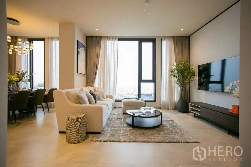 คอนโด ให้เช่าในWatthana, Bangkok - ห้องนั่งเล่นสว่าง มีหน้าต่างสูงจรดเพดาน โซฟา ผนังทีวี และวิวเมือง