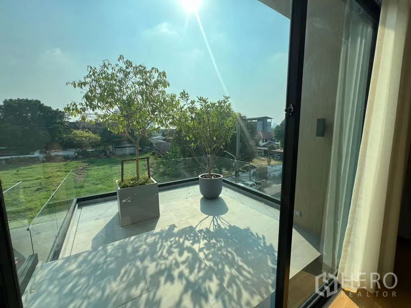 Detached House for sale in Suan Luang, Bangkok - Sunny balcony terrace with glass railing, potted trees and neighborhood view