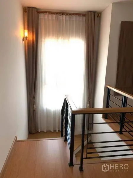 บ้าน ขายในSuan Luang, Bangkok - โถงบันได ราวไม้กับโครงเหล็ก และหน้าต่างติดม่านโปร่ง