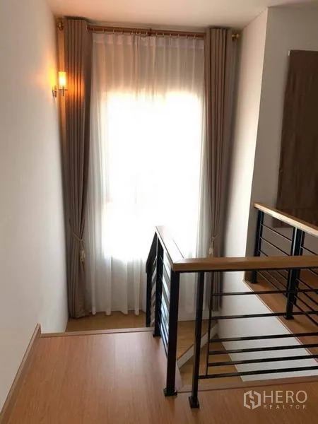 บ้าน ขายในSuan Luang, Bangkok - โถงบันได ราวไม้กับโครงเหล็ก และหน้าต่างติดม่านโปร่ง