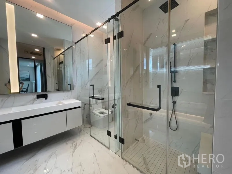 Detached House for rent in Bueng Kum, Bangkok - Luxurious bathroom with marble-look tiles, floating vanity and dual glass shower enclosures with rain shower.