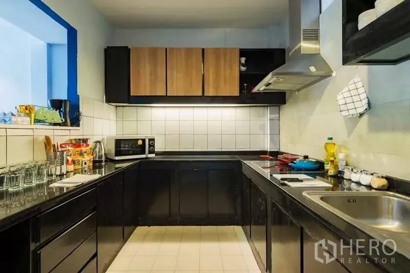 联排别墅 出租在Watthana, Bangkok - U形厨房，黑色柜体、瓷砖防溅板与抽油烟机。
