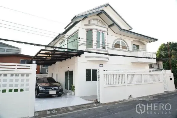 Detached House for sale in Bang Bon, Bangkok - Detached house with a car parked under the covered carport beside the fence.