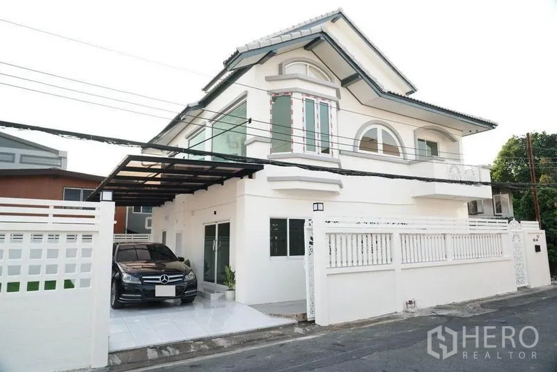 Detached House for sale in Bang Bon, Bangkok - Detached house with a car parked under the covered carport beside the fence.