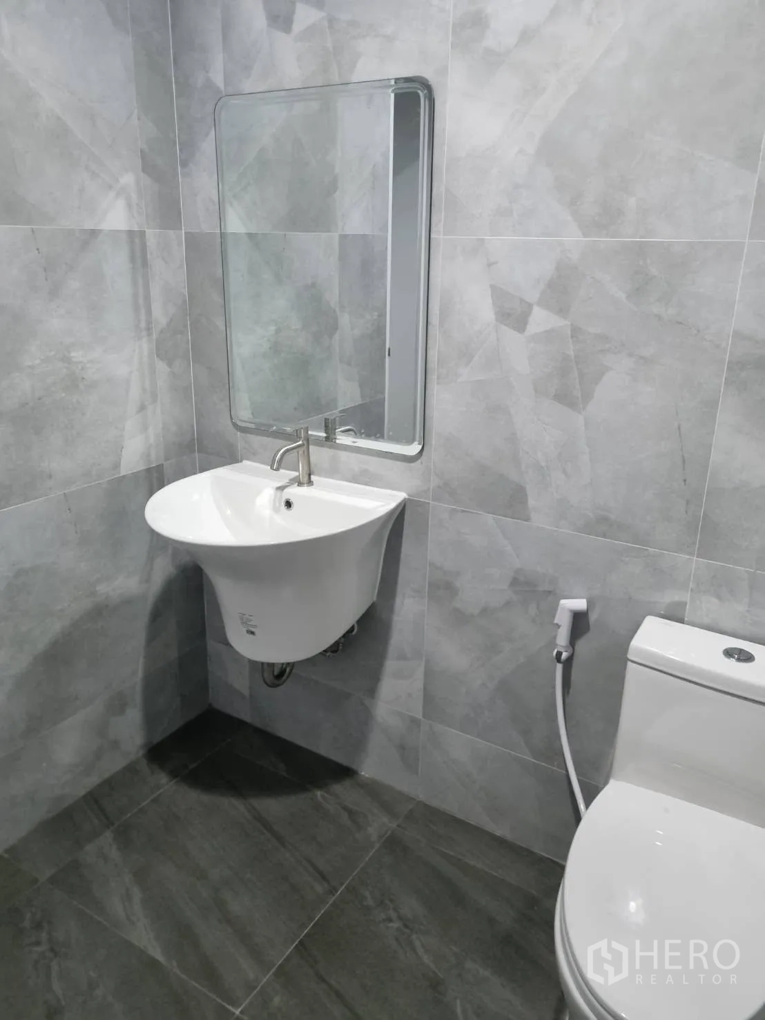 Warehouse for rent in Thepharak, Nakhon Ratchasima - Tiled restroom with wall-mounted sink, mirror, and toilet.