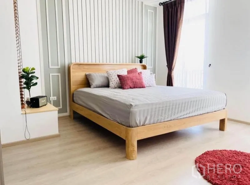 联排别墅 出租在Prawet, Bangkok - 宽敞卧室，木床、竖纹墙板与阳台采光。