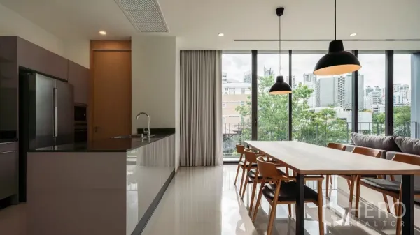 Condominium for rent in Bang Kapi, Bangkok - Bright open-plan kitchen and dining area with floor-to-ceiling windows, pendant lights and city and treetop views.