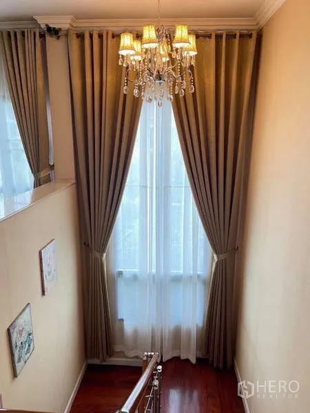 独立式住宅 出租在Mueang Nonthaburi, Nonthaburi - 楼梯间高窗与长窗帘，配水晶吊灯。