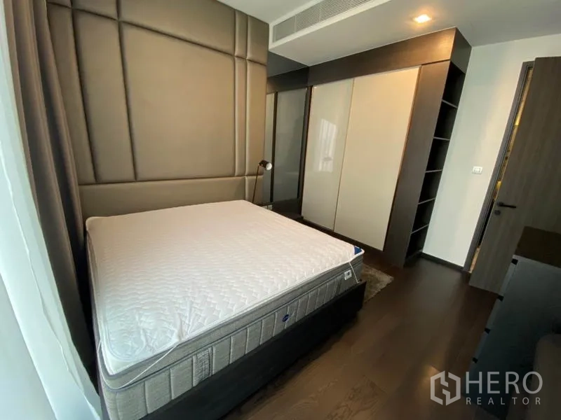 Condominium for rent in Watthana, Bangkok - Bedroom with large wardrobe, bedside shelving and soft recessed lighting.
