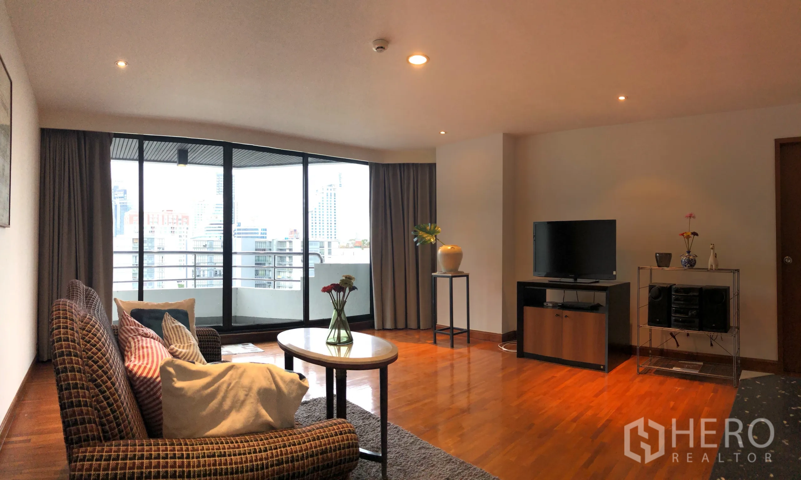 คอนโด ให้เช่าในKhlong Toei, Bangkok - พื้นที่นั่งเล่นพร้อมประตูกระจกสูงเปิดสู่ระเบียง มีทีวีและโต๊ะกลาง