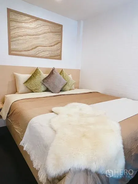 公寓 出租或出售在Khlong Toei, Bangkok - 温馨卧室，米色床品与靠枕，床头装饰画点缀。