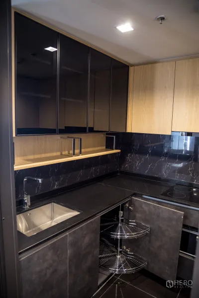 คอนโด ให้เช่าในChatuchak, Bangkok - ครัวรูปตัวแอล ผนังลายหินอ่อนสีดำ เตาไฟฟ้า และชั้นเก็บของมุมแบบคารูเซล
