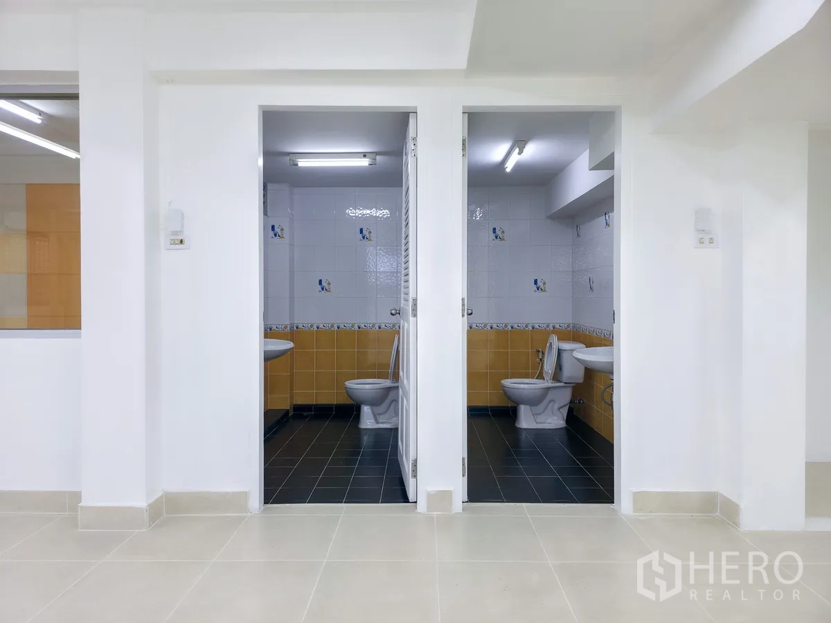 办公室 for rent in Khlong Toei, Bangkok - 两个独立卫生间，配坐便器与洗手盆，瓷砖墙面。