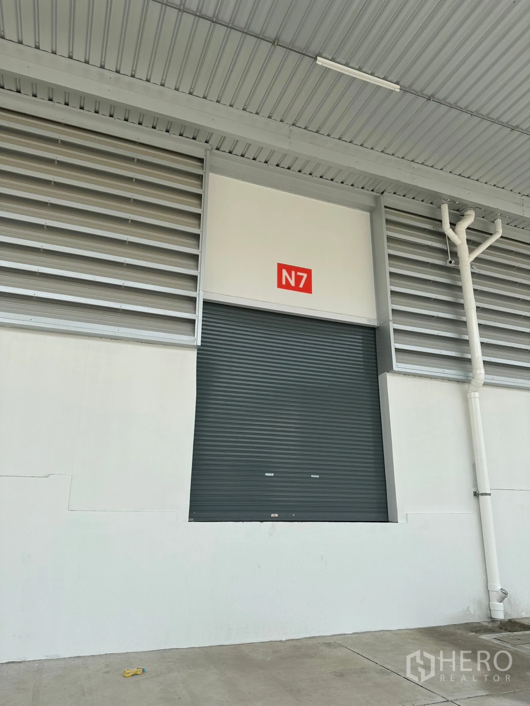 Factory for rent in Khlong Luang, Pathum Thani - Single warehouse loading bay labeled N7 with insulated roller shutter under metal canopy.