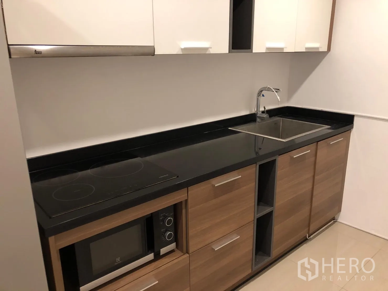 คอนโด ให้เช่าในWatthana, Bangkok - เคาน์เตอร์ท็อปหินสีดำ เตาไฟฟ้า ไมโครเวฟ และตู้ลายไม้
