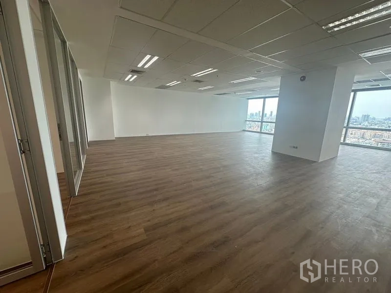 สำนักงาน ให้เช่า - พื้นที่เปิดโล่งขนาดใหญ่ มีหน้าต่างสองด้านและไฟฟลูออเรสเซนต์บนเพดาน.