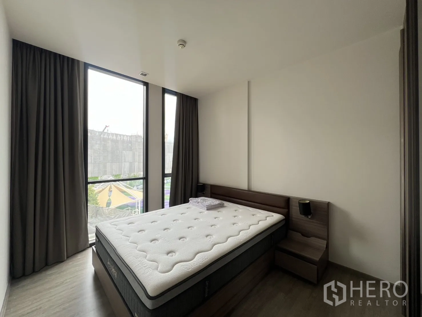 คอนโด for rent in Watthana, Bangkok - ห้องนอนมุมอาคารพร้อมหน้าต่างสูงสองด้าน โต๊ะหัวเตียง และผ้าม่าน