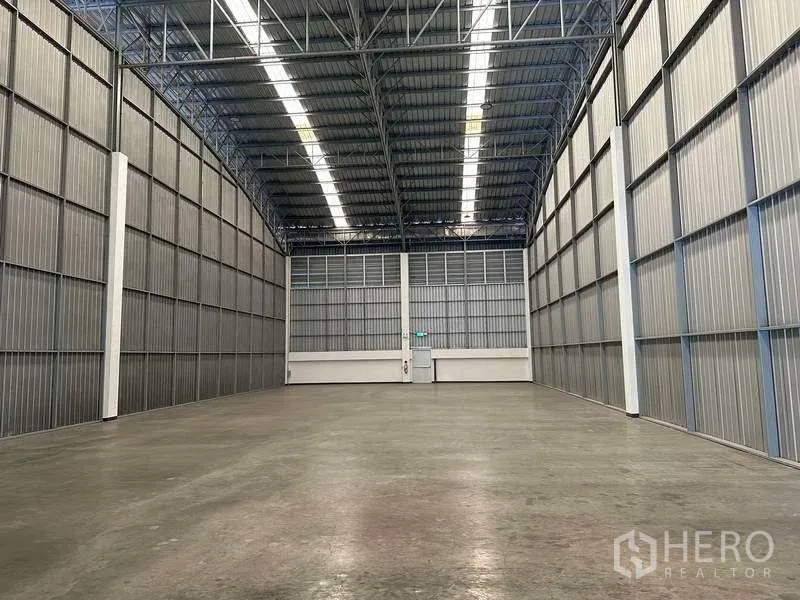 Factory for rent in Bang Sao Thong, Samut Prakan - Clear-span warehouse interior with steel truss roof and continuous lighting.